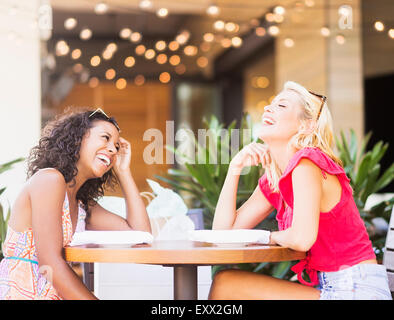 Female friends laughing in street cafe Banque D'Images