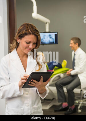 Portrait de dentiste avec un collègue et patient (8-9) en arrière-plan Banque D'Images