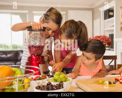 Enfants (2-3, 6-7, 8-9) la préparation de cocktails de fruits Banque D'Images