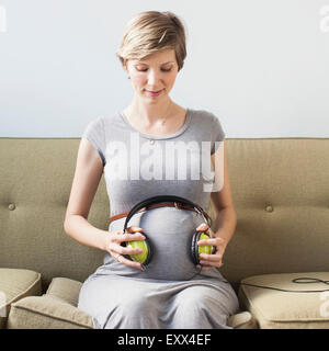 Pregnant woman holding casque sur l'abdomen Banque D'Images