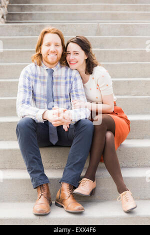 Smiling couple sitting on steps Banque D'Images