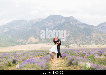 Newlywed couple kissing in champ de lavande avec des montagnes en arrière-plan Banque D'Images