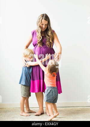 Enfants (2-3) hugging pregnant mother Banque D'Images
