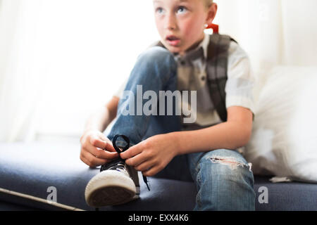 Boy (6-7) chaussures de liage Banque D'Images