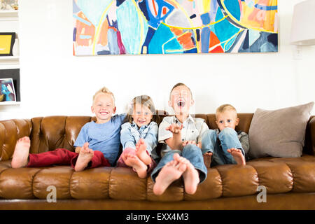 Smiling Children (2-3, 4-5, 6-7) sitting on sofa Banque D'Images