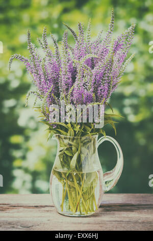 Bouquet de fleurs sauvages en pot sur une vieille table en bois. Vintage stylisée. Banque D'Images