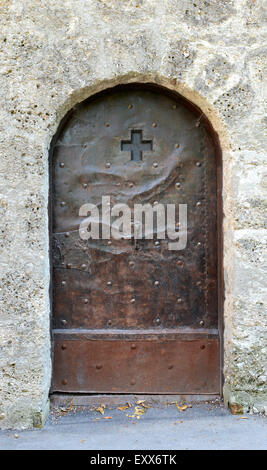 Ancienne porte de métal clouté, décoré d'une croix et la gravure, dans un mur de pierre à Salzbourg, Autriche Banque D'Images