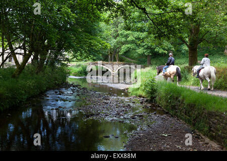 Deux cavaliers crossing Wycoller Beck, Breistroff-la-Grande, Lancashire Banque D'Images