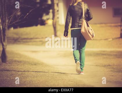 Jeune fille en pantalon vert en marche dans la ville. Photographié par derrière Banque D'Images