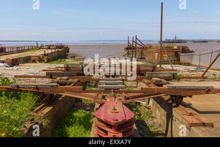 Ship yard désaffecté avec épaves de navires en fer rouille et flanquée de treuil de banques de boue de l'estuaire Humber. Banque D'Images