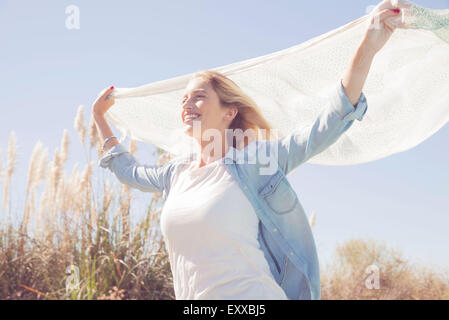 Woman holding up foulard voltigeant dans le vent Banque D'Images