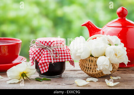 Red Teapot, pots de confiture, Panier de roses bouquet et tasse de thé. Banque D'Images