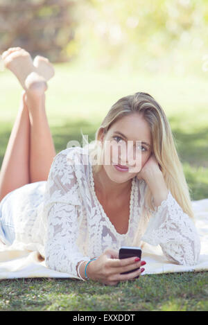 Young woman relaxing in park with smartphone Banque D'Images