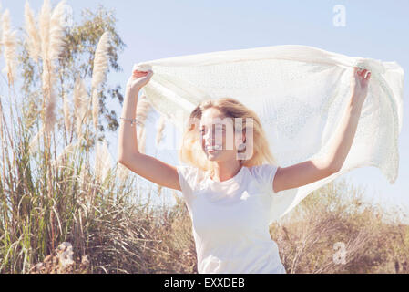 Woman holding up foulard voltigeant dans le vent Banque D'Images