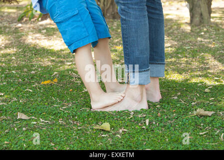 Petit garçon debout pieds nus sur pieds du père, cropped Banque D'Images