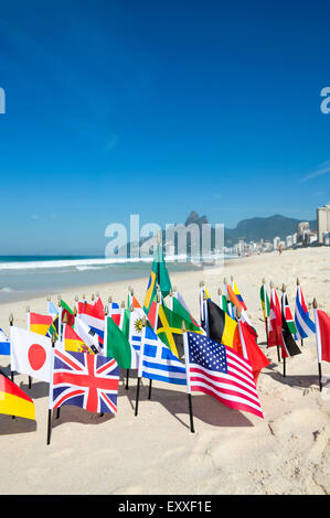 Drapeaux internationaux voler avec drapeau brésilien sur le sable contre une vue sur l'horizon de la plage d'Ipanema à Rio de Janeiro, Brésil Banque D'Images