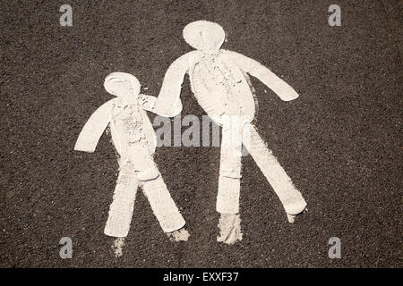 Les chiffres de l'enfant et le parent se tenant la main sur la chaussée goudronnée, marmonne, South Wales, UK Banque D'Images