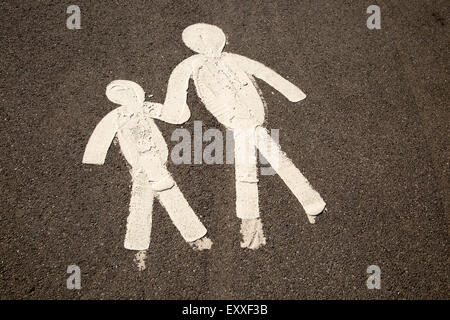 Les chiffres de l'enfant et le parent se tenant la main sur la chaussée goudronnée, marmonne, South Wales, UK Banque D'Images