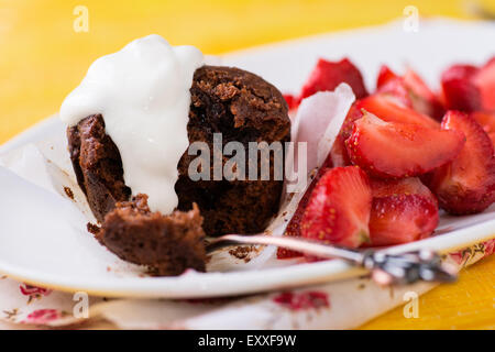 Muffins au chocolat avec des noix et de cerises, fraises sur le côté, fond jaune, selective focus Banque D'Images