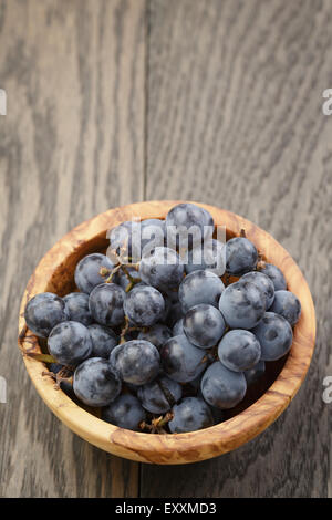 Les raisins mûrs isabella dans bol sur la table en bois Banque D'Images