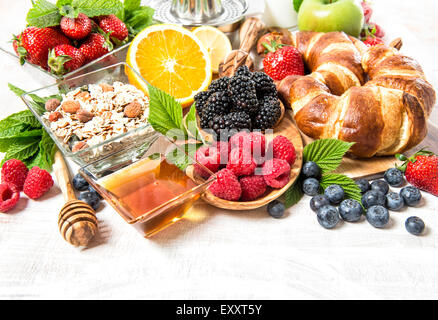 Le petit-déjeuner avec croissants, céréales, jus de fruits, petits fruits orange, pomme, lait. La nutrition saine Banque D'Images