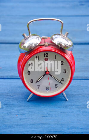 Réveil ancien style rouge sur bleu table de jardin en bois Banque D'Images