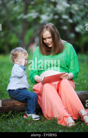 Mère enceinte avec petit-fils sur le bloc de touches dans le parc Banque D'Images