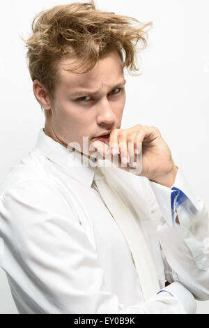 Un beau jeune homme, modèle masculin, vêtu d'une chemise blanche avec cravate blanche, cheveux en désordre à la malade Banque D'Images