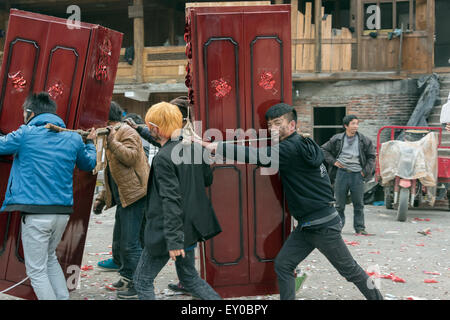 Les jeunes, couverts de suie firecracker transportant des meubles de mariage, village Dong de Huanggang, province de Guizhou, Chine Banque D'Images