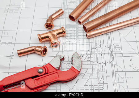 Outils de plomberie disposées sur des plans de maison, avec des tubes en cuivre Banque D'Images