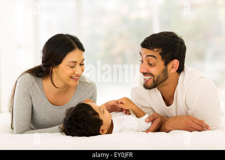 Happy young Indian family lying on bed Banque D'Images