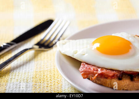 Toast avec les œufs et le bacon sur une assiette blanche Banque D'Images