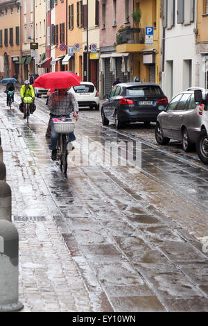 Les cyclistes équitation dans la pluie avec des parapluies ou des vêtements par temps humide. Banque D'Images