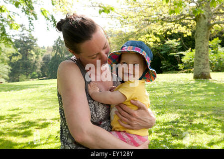 Mère de câliner son bébé dans le le jardin sur une belle journée d'été Banque D'Images