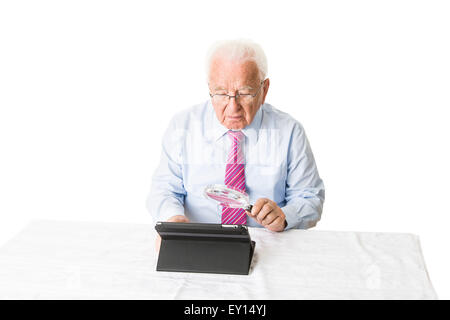 À l'aide d'un ordinateur tablette senior avec une loupe Banque D'Images