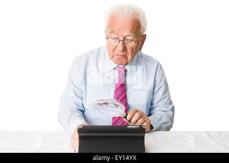 À l'aide d'un ordinateur tablette senior avec une loupe Banque D'Images