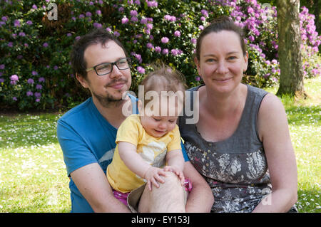 Portrait de couple heureux avec leur fille de bébé, dans de beaux jardins Banque D'Images