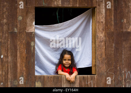 Cute little girl sur sa fenêtre en bois l'accueil souriant à l'appareil photo à El Castillo, Nicaragua Banque D'Images