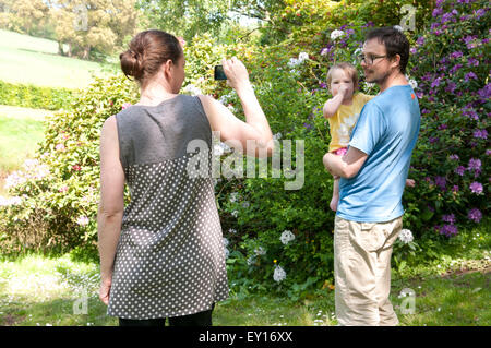 Maman de prendre une photo sur son portable de sa partenaire et petite fille à l'extérieur dans le jardin Banque D'Images