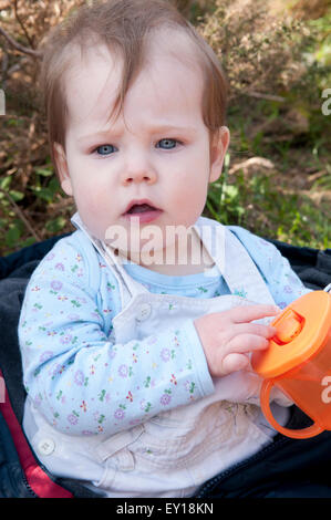 Baby Girl sitting up sans aide à jouer avec son entraîneur cup Banque D'Images