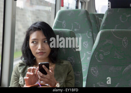 Woman with mobile phone dans le bus vide Banque D'Images