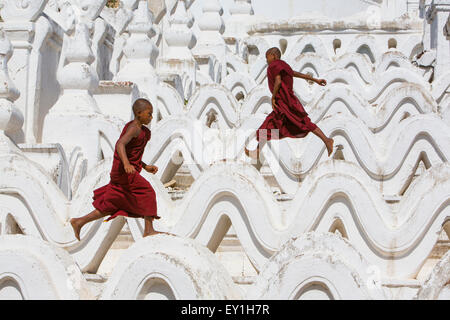 Robe rouge moines novices sautant vagues à Hsinbyume Paya temple, Mandalay, Myanmar Banque D'Images
