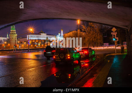 Voitures sous le grand pont de pierre sur la rivière de Moscou. Kremlin de Moscou dans l'ombre à la nuit d'hiver Banque D'Images