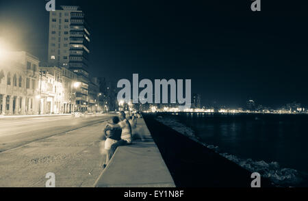 Le long du Malecon, La Havane, Cuba, les gens, la nuit, l'air de la mer chaude de la mer assis sur le mur en face de bâtiments coloniaux avec Banque D'Images