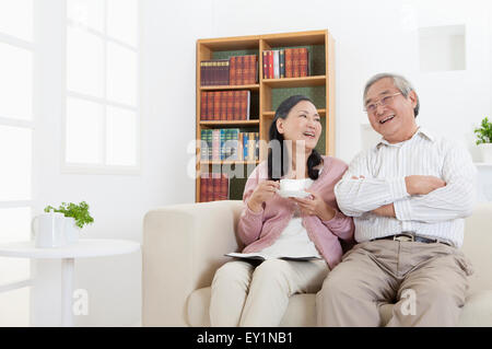 Senior couple sitting on sofa et heureusement, smiling Banque D'Images