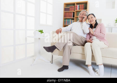 Couple assis sur le canapé et à l'écart avec sourire, Banque D'Images