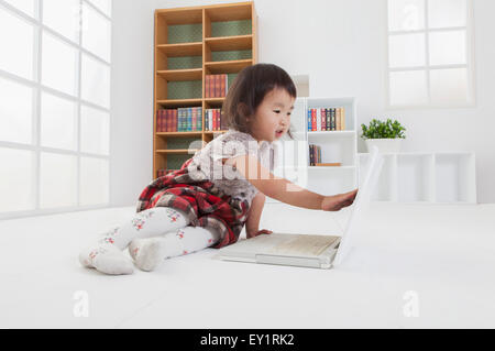 Petite fille assise et à l'ordinateur portable, Banque D'Images