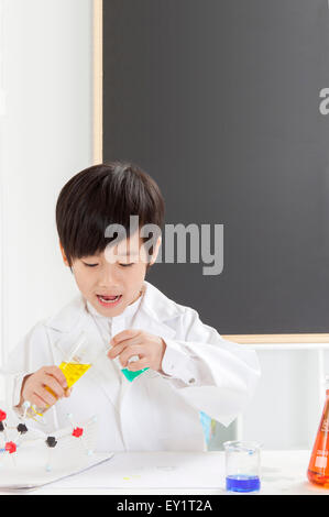 Boy doing experiment et regardant en bas avec le sourire Banque D'Images