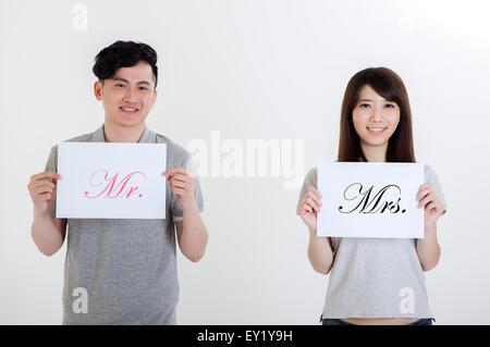 Young couple holding white board et souriant à la caméra, Banque D'Images