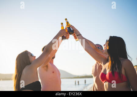 Groupe de jeunes amis multiethnique les femmes et les hommes à la plage en été, le grillage avec quelques bières sur l'estran - amitié, détente, concepts happy hour Banque D'Images